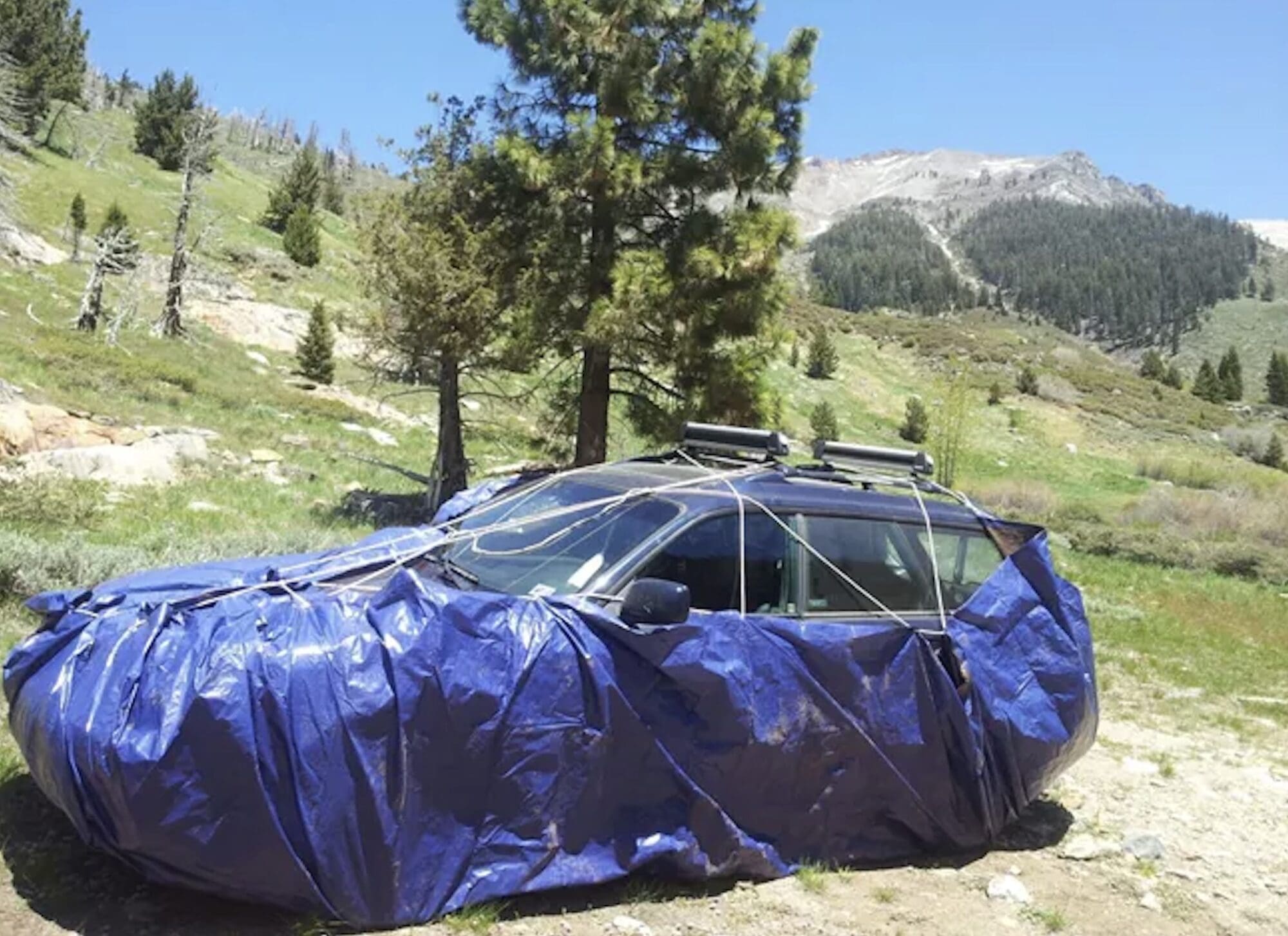 Vehicle wrapped in tarp to prevent marmot intrusion.