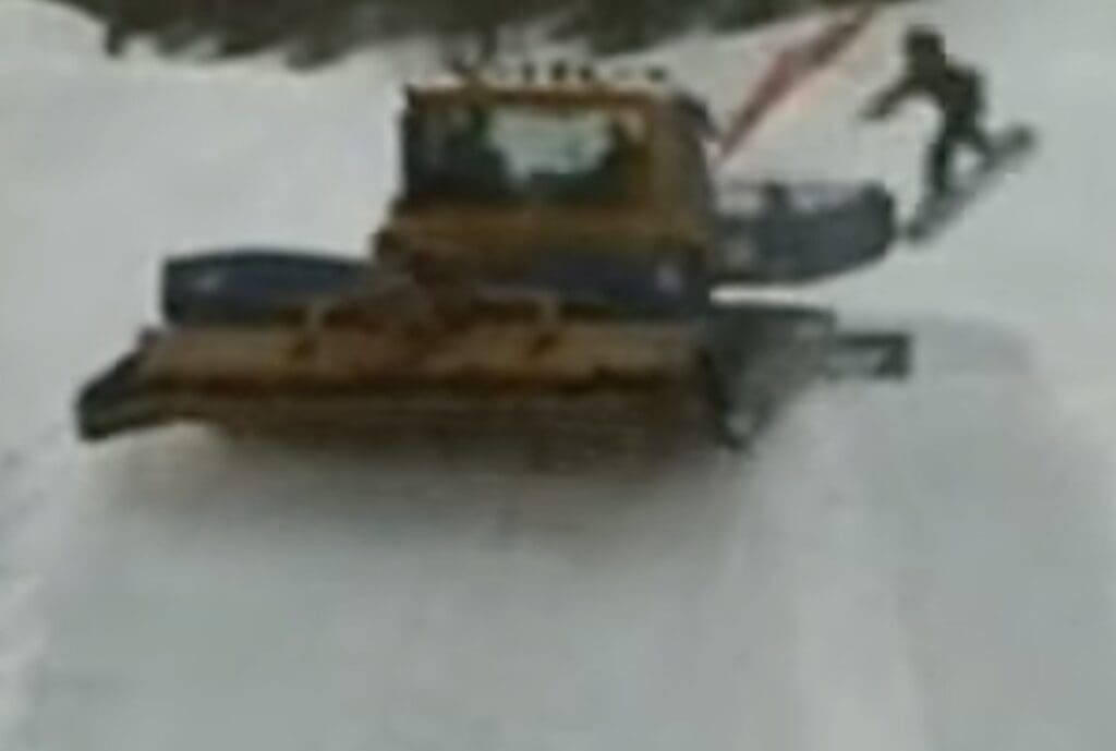 Snowboarder narrowly misses snowcat.