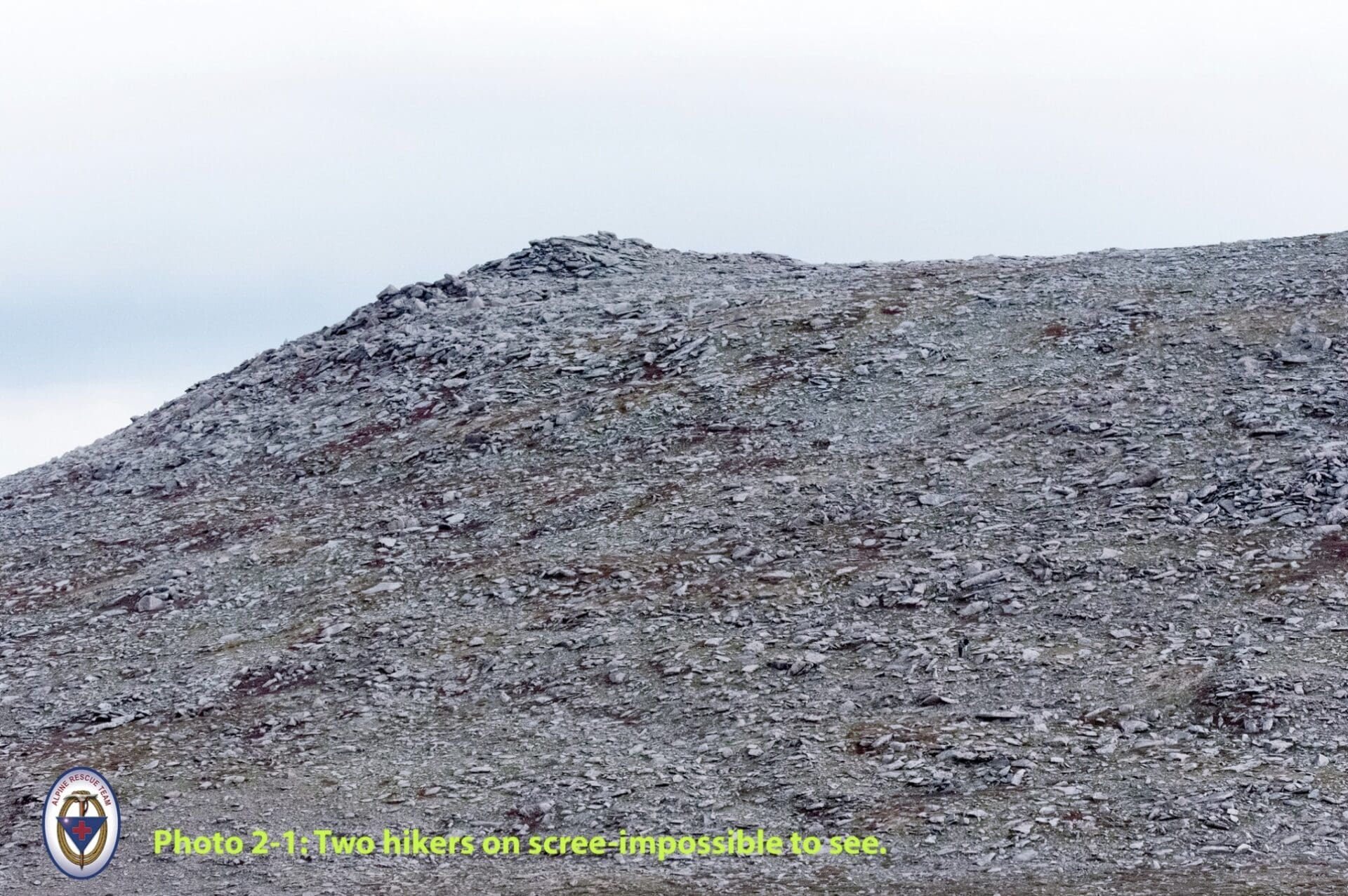 Two near-invisible hikers on scree.