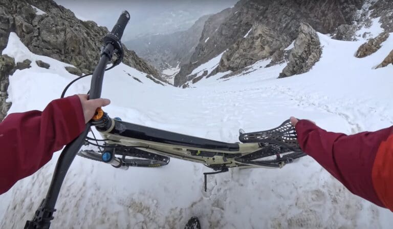 Mountain biker rides steep snowy couloir
