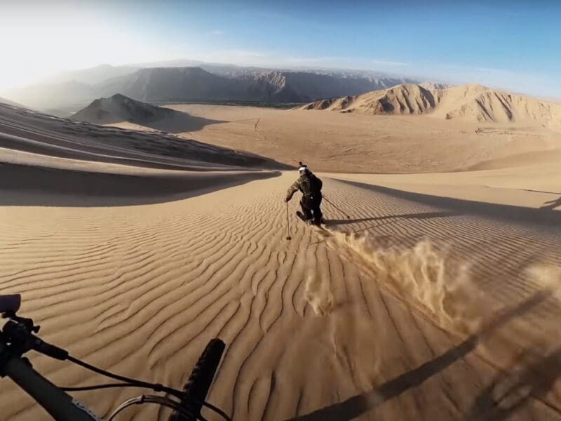 Biker Kilian Bron and skier Victor Broquedis race down Cerra Blanco dune in Peru.