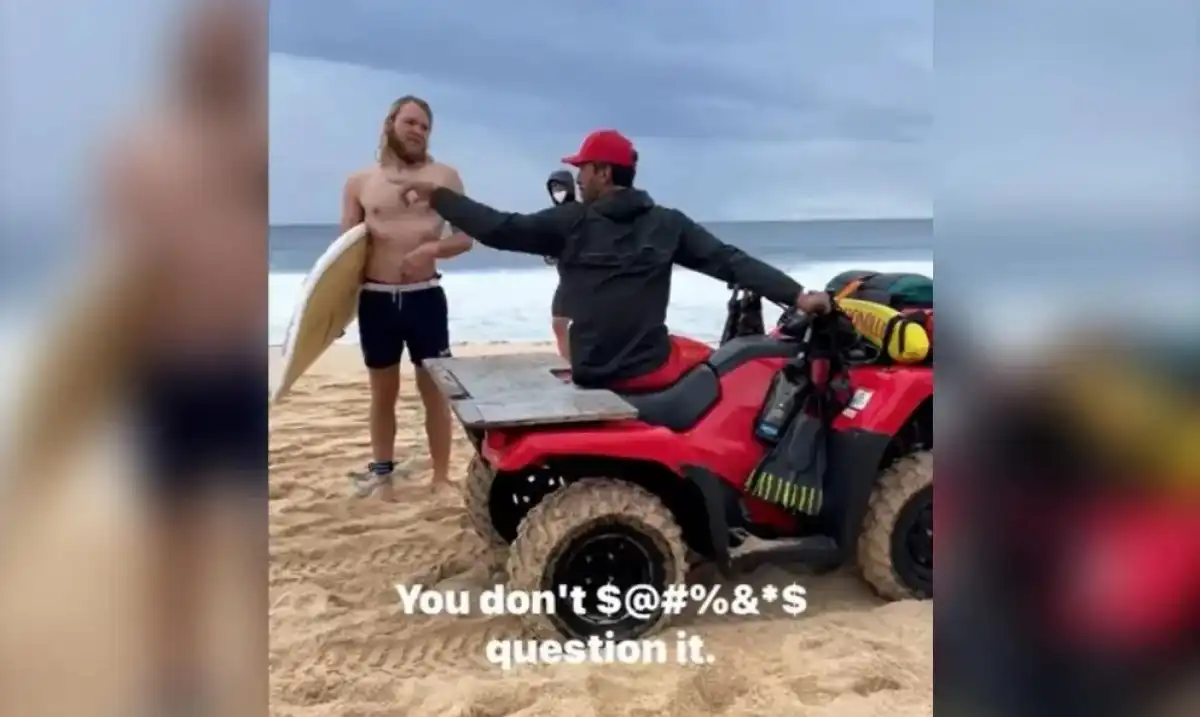 Lifeguard berates surfers for disobeying his directions.