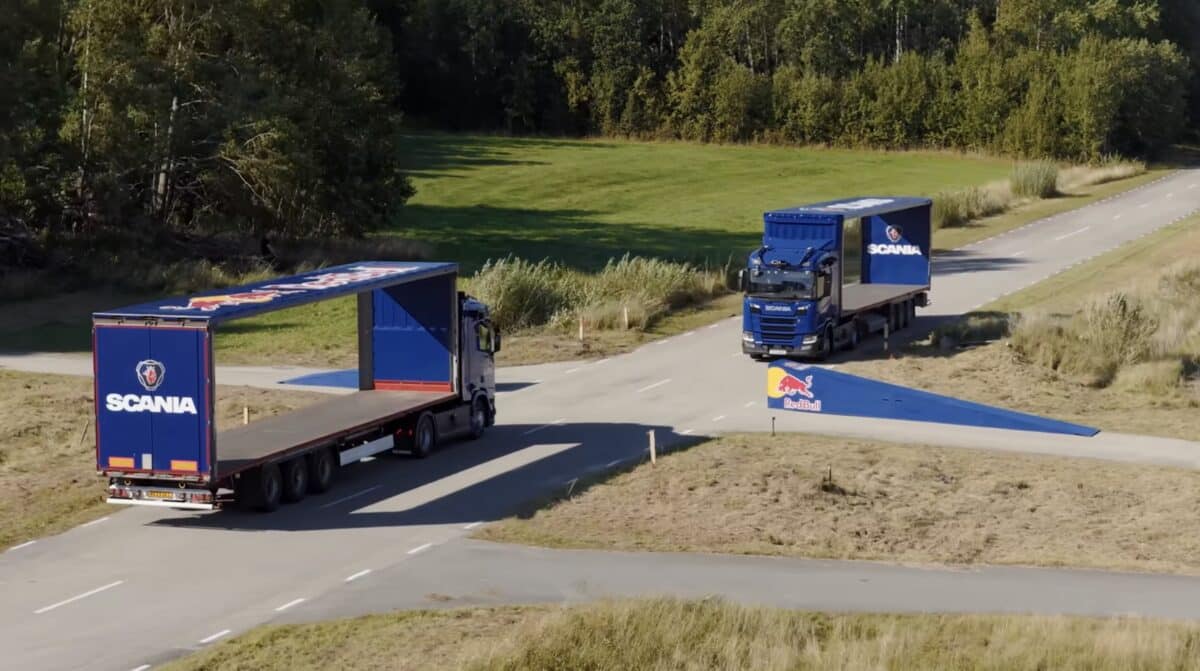 Mountain biker jumps through moving semi-trailers