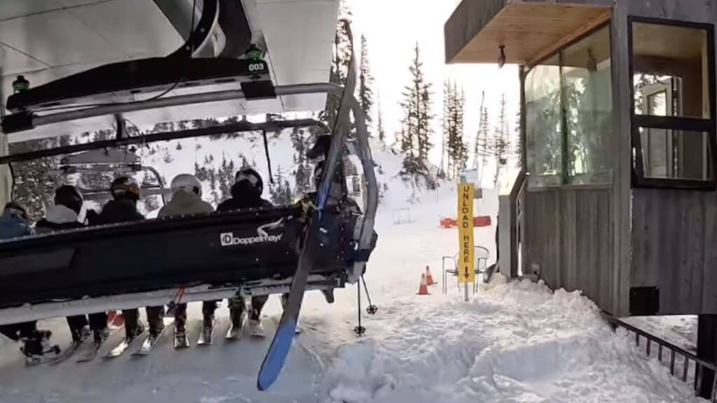 Flying ski strikes snowboarder on the chairlift behind.
