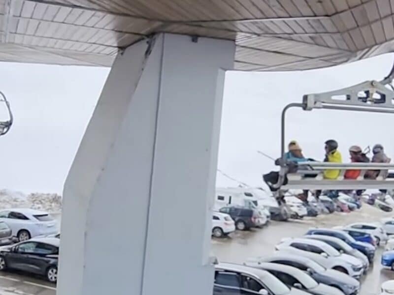 Chairlift takes a 90-degree turn over a parking lot.