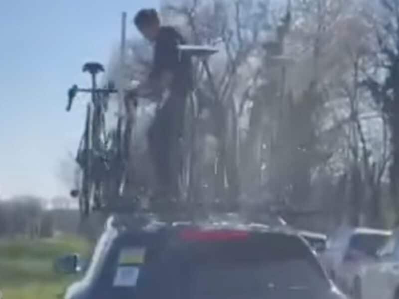 Drunk spectators attempt to steal bike from team car at cycling race.