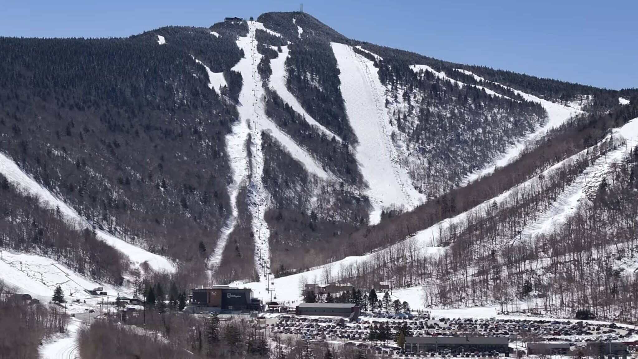 Snowy alpine slopes with ski runs and a base village at the foothills.