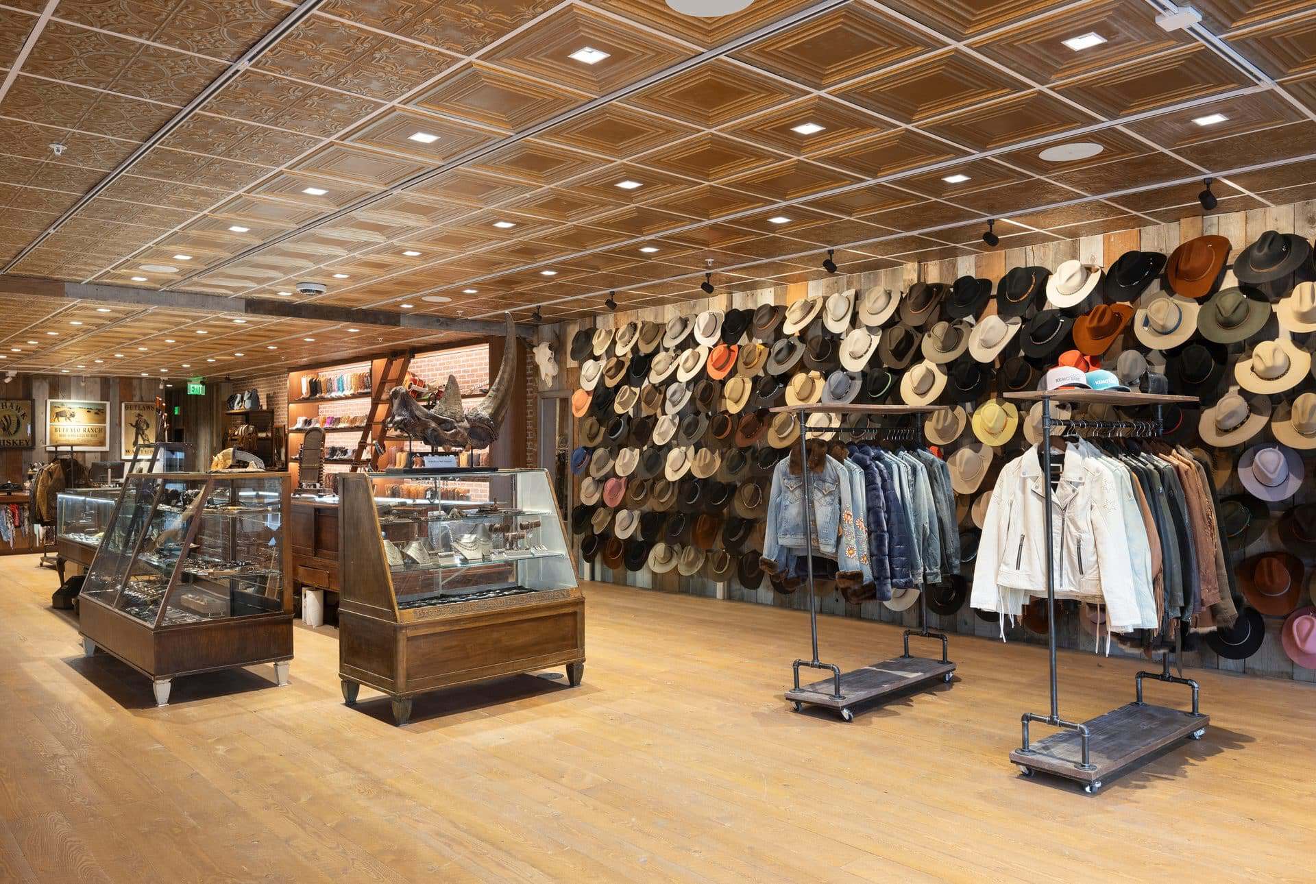 Indoor hat shop with a wall full of hats and clothing racks.