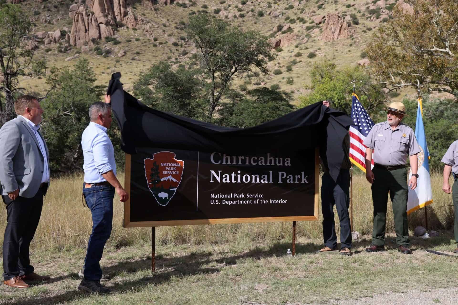 Group unveiling Chiricahua National Park sign with officials and park staff.