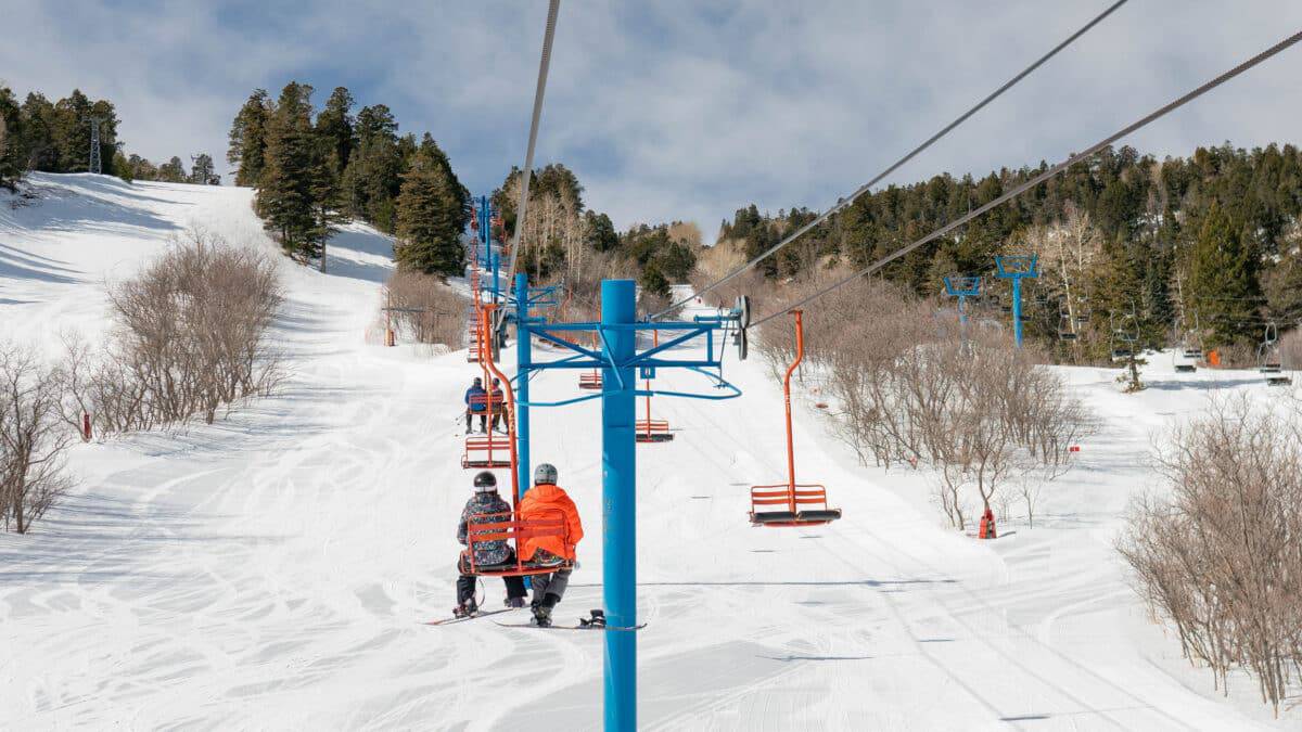 Ski lift at Sandia Peak with snow-covered slopes and trees.