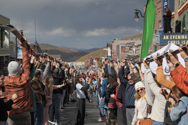 Crowd participating in après ski celebration with raised hands in mountain town.