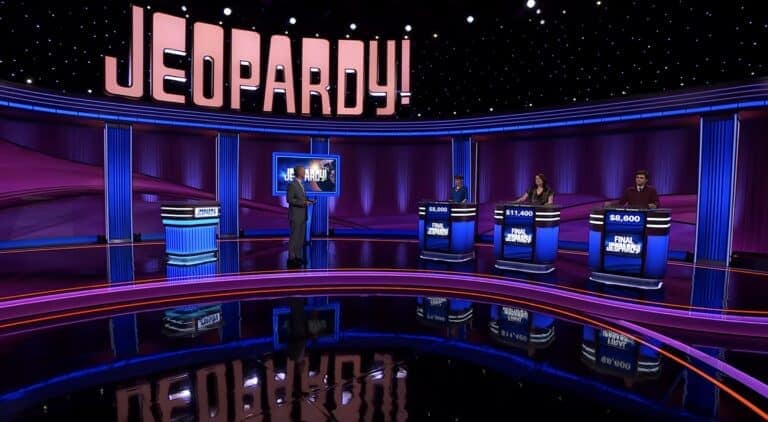 Jeopardy! game show with contestants and host on stage.