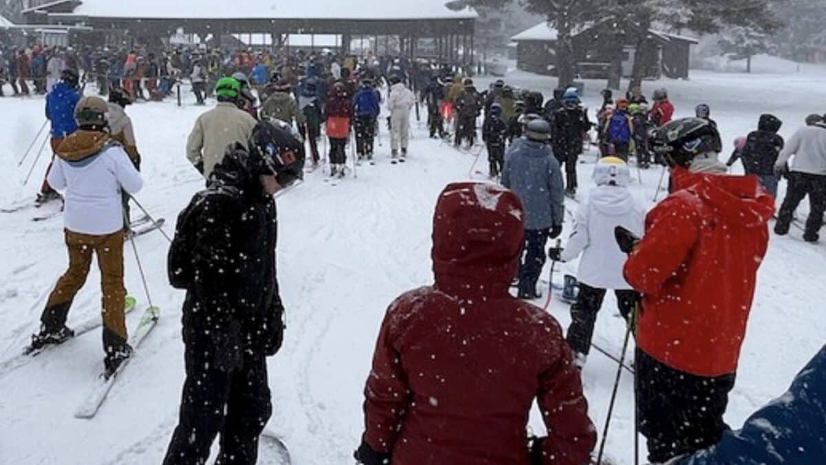 Large group of skiers and snowboarders gathering at snowy mountain resort.
