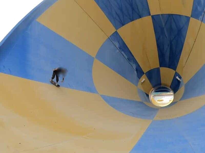 Skateboarder riding inside a colorful, empty waterpark funnel slide.
