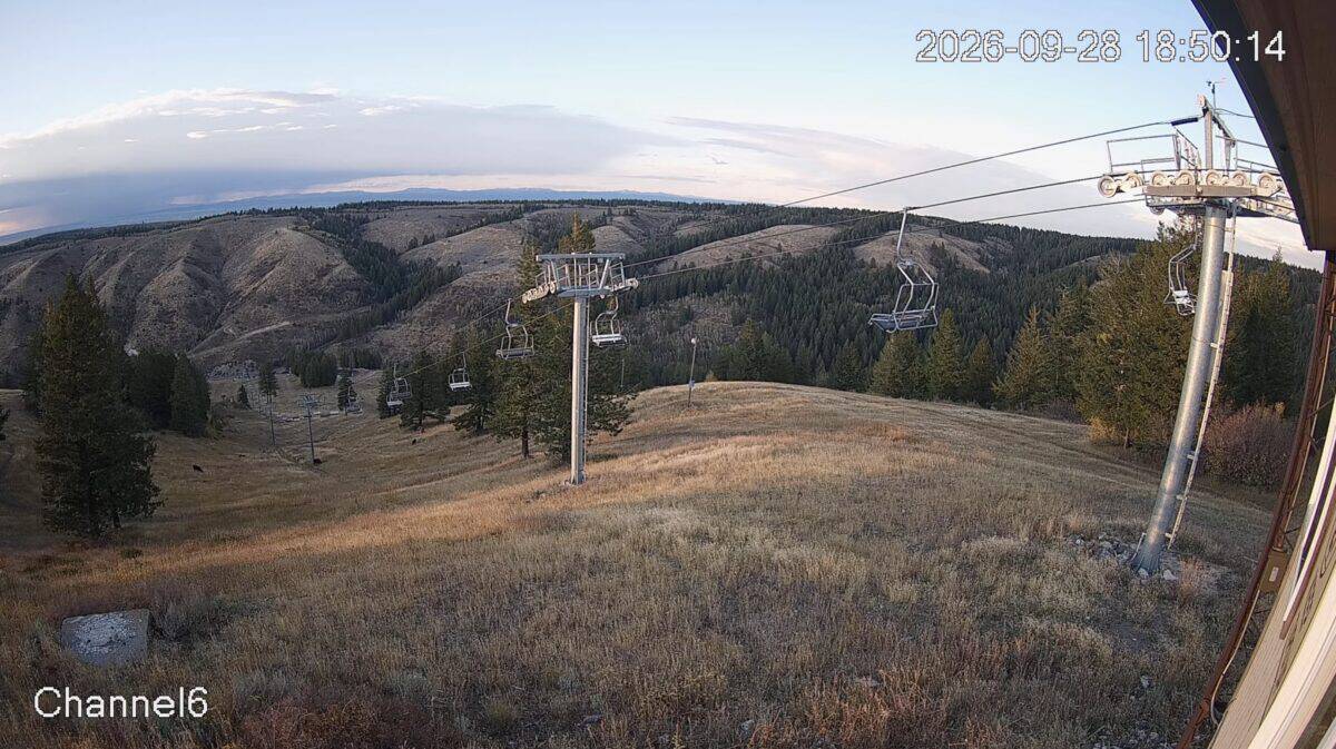 Mountain landscape with ski lift and open slopes at sunset.