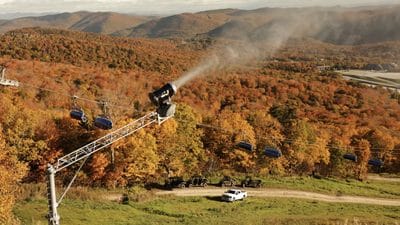 Gondola lift traveling over colorful fall foliage in mountain landscape.