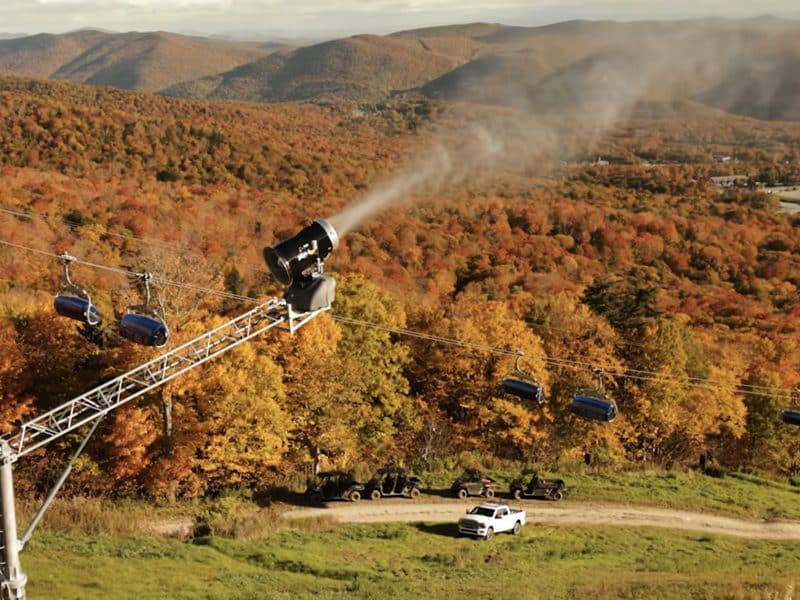 Gondola lift traveling over colorful fall foliage in mountain landscape.