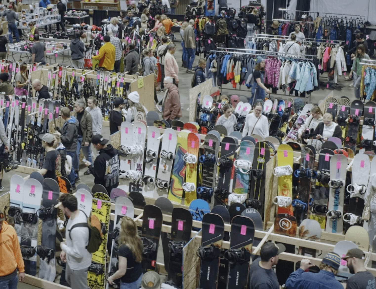 Crowd shopping for skis, snowboards, and outdoor gear at a busy market.