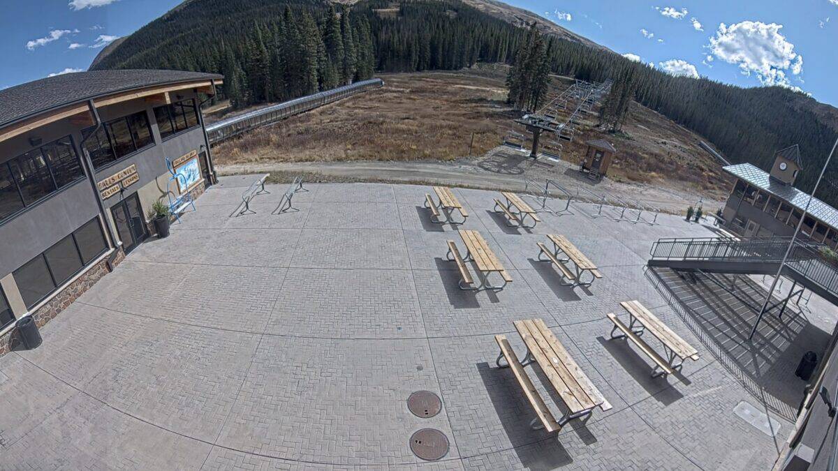 Empty outdoor public space with picnic tables and mountain backdrop.