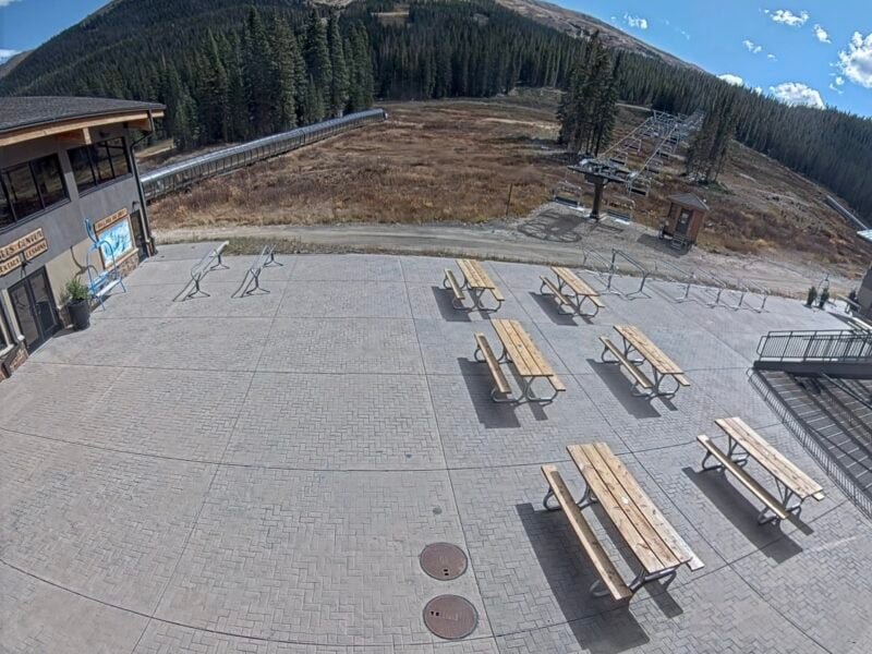 Empty outdoor public space with picnic tables and mountain backdrop.