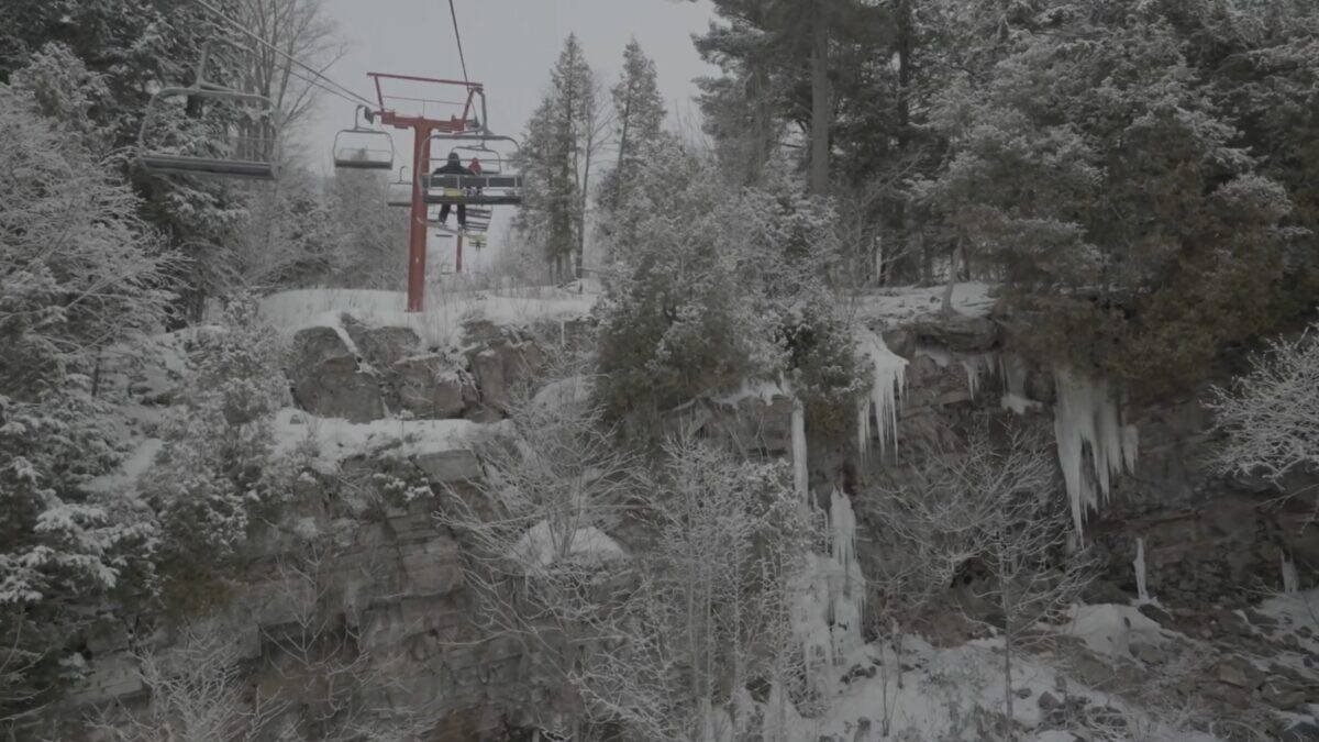 Ski lift over snow-covered trees and rocks in a winter mountain scene.