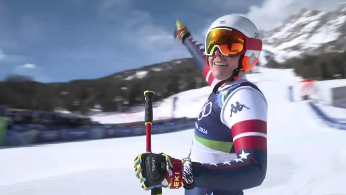 Happy snowboarder in gear on snowy mountain with blue sky background.