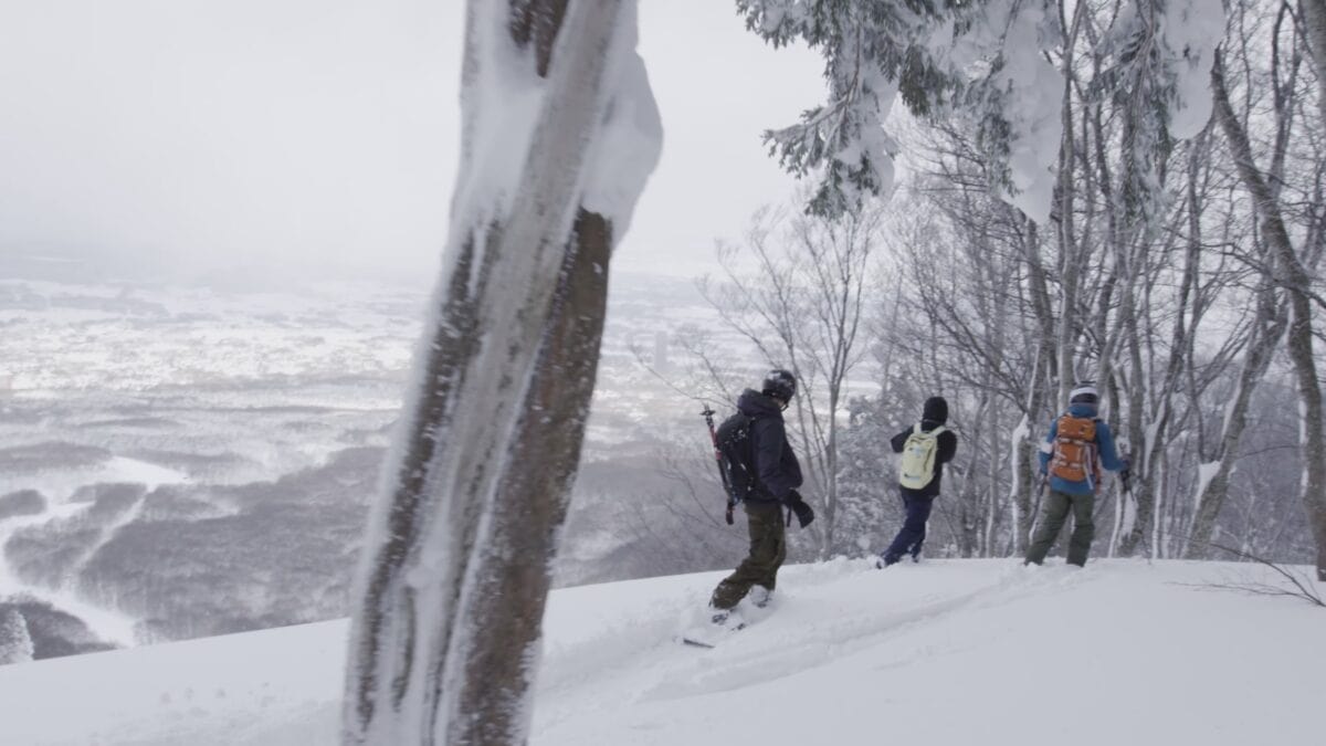 Hikers walking on snow-covered trail in winter landscape.