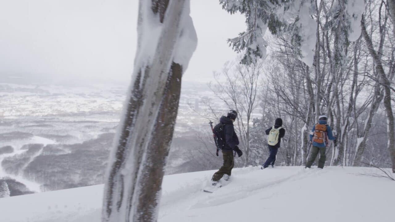 Hikers walking on snow-covered trail in winter landscape.