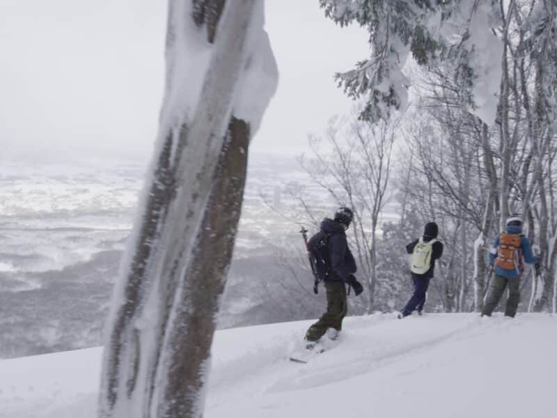 Hikers walking on snow-covered trail in winter landscape.