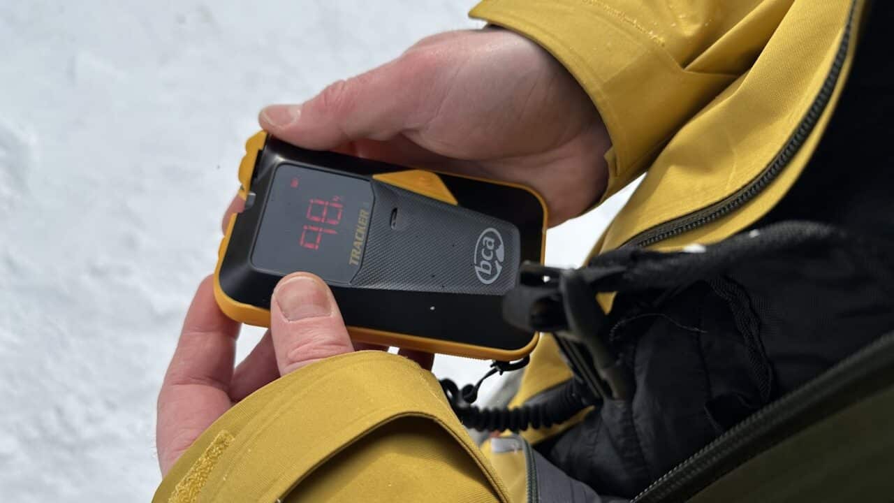 Person using a portable breathalyzer device outdoors in mountain terrain.