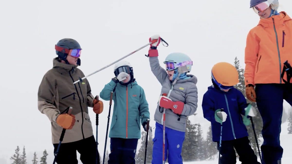 Family enjoying skiing in snowy mountain with ski gear and helmets.