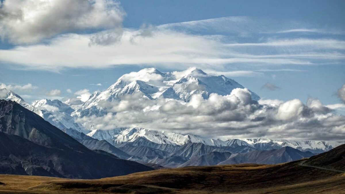 Snow-covered mountains under a partly cloudy sky in a mountain landscape.