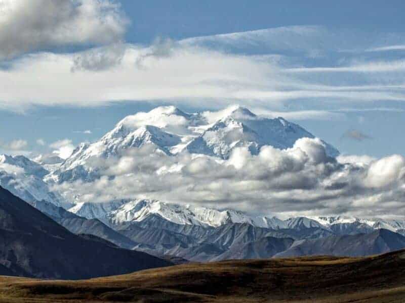 Snow-covered mountains under a partly cloudy sky in a mountain landscape.