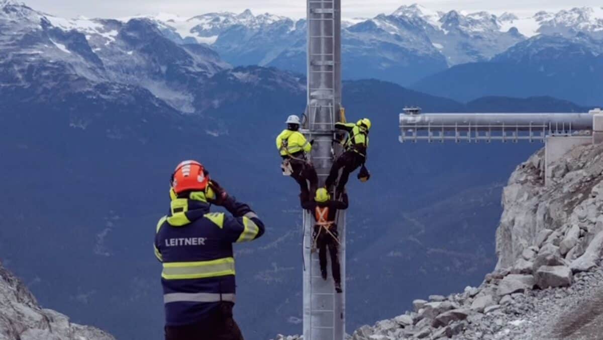 Rescue team assists climber on mountain construction site with scenic background.