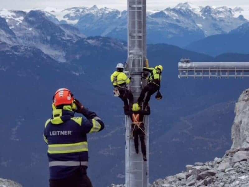 Rescue team assists climber on mountain construction site with scenic background.