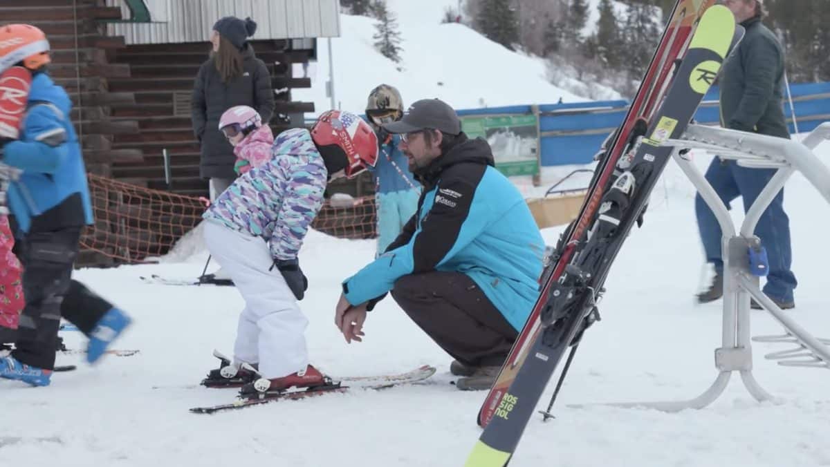 Children learning to ski with instructor at snowy mountain resort.