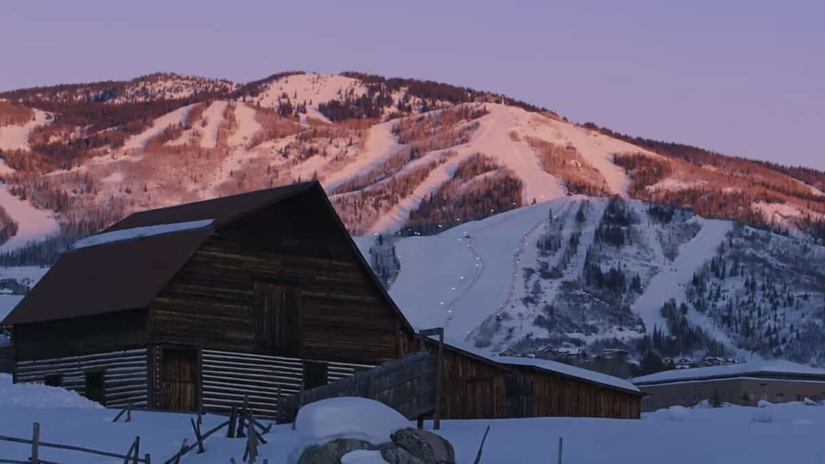 Snowy mountain landscape with a wooden cabin in the foreground.