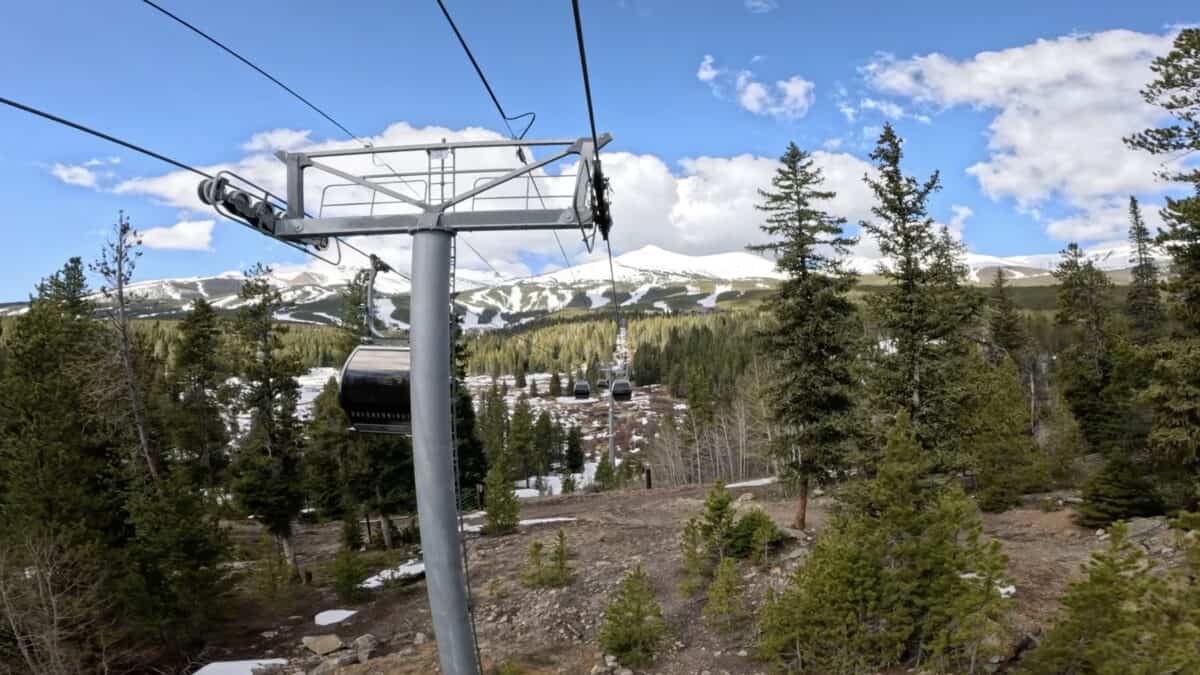 Gondola lift at Breck with pine trees and snowy peaks in the background.
