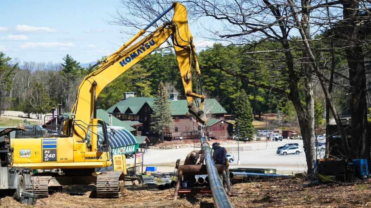 Heavy construction machinery working near trees at a mountain resort.