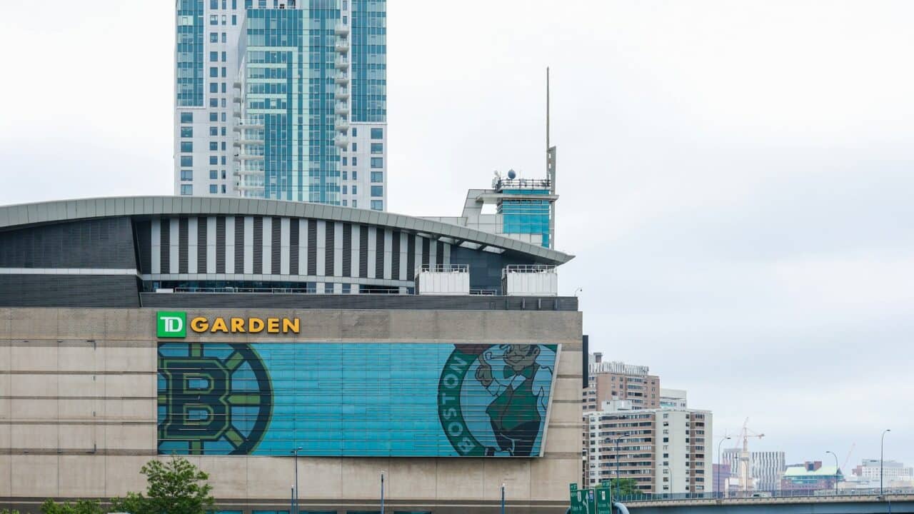 Boston TD Garden with city skyline and skyscrapers in background.